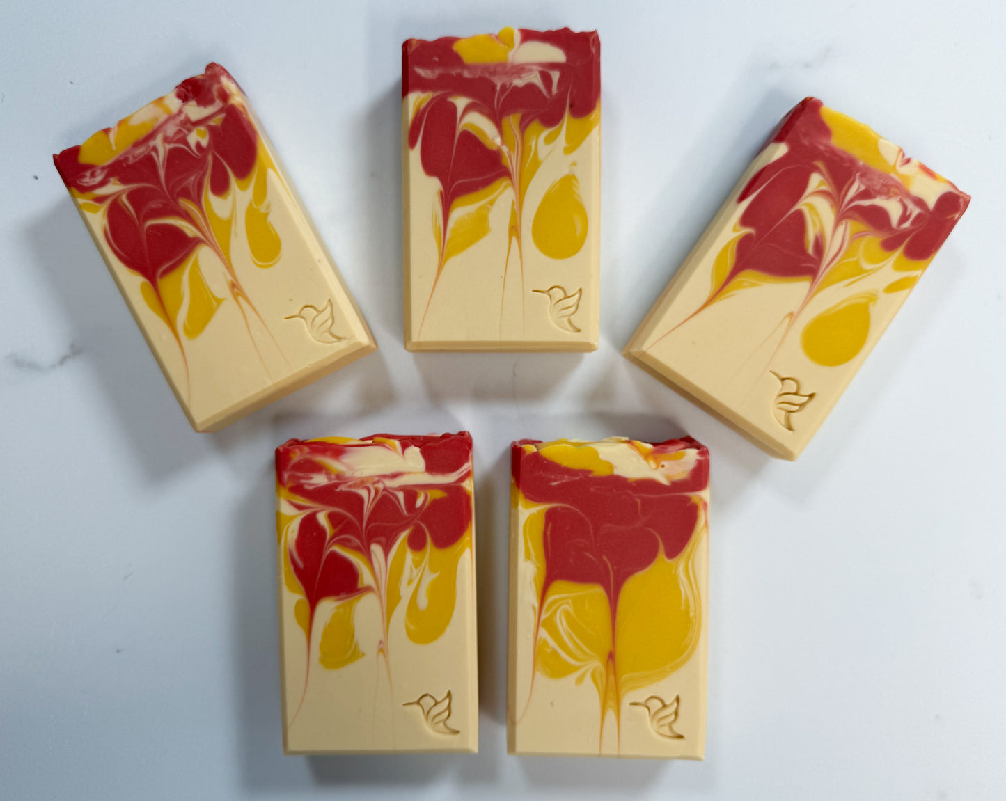 Five bars of Sunlit Citrus goat milk and tallow soap featuring vibrant pink, red, and golden citrus-inspired swirls.