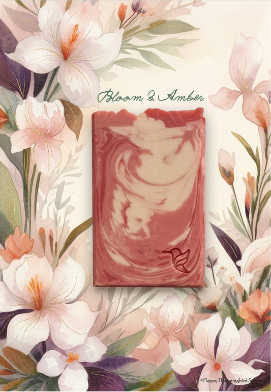 Bloom and Amber artisan soap bar with pink and cream marbling, displayed against a soft watercolor background of elegant irises and floral blooms.
