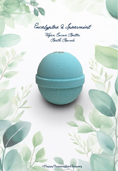 Close-up of pale blue-green spherical Eucalyptus & Spearmint Oat Milk Bath Bomb, set within a botanical border by Happy Hummingbird Soapery.