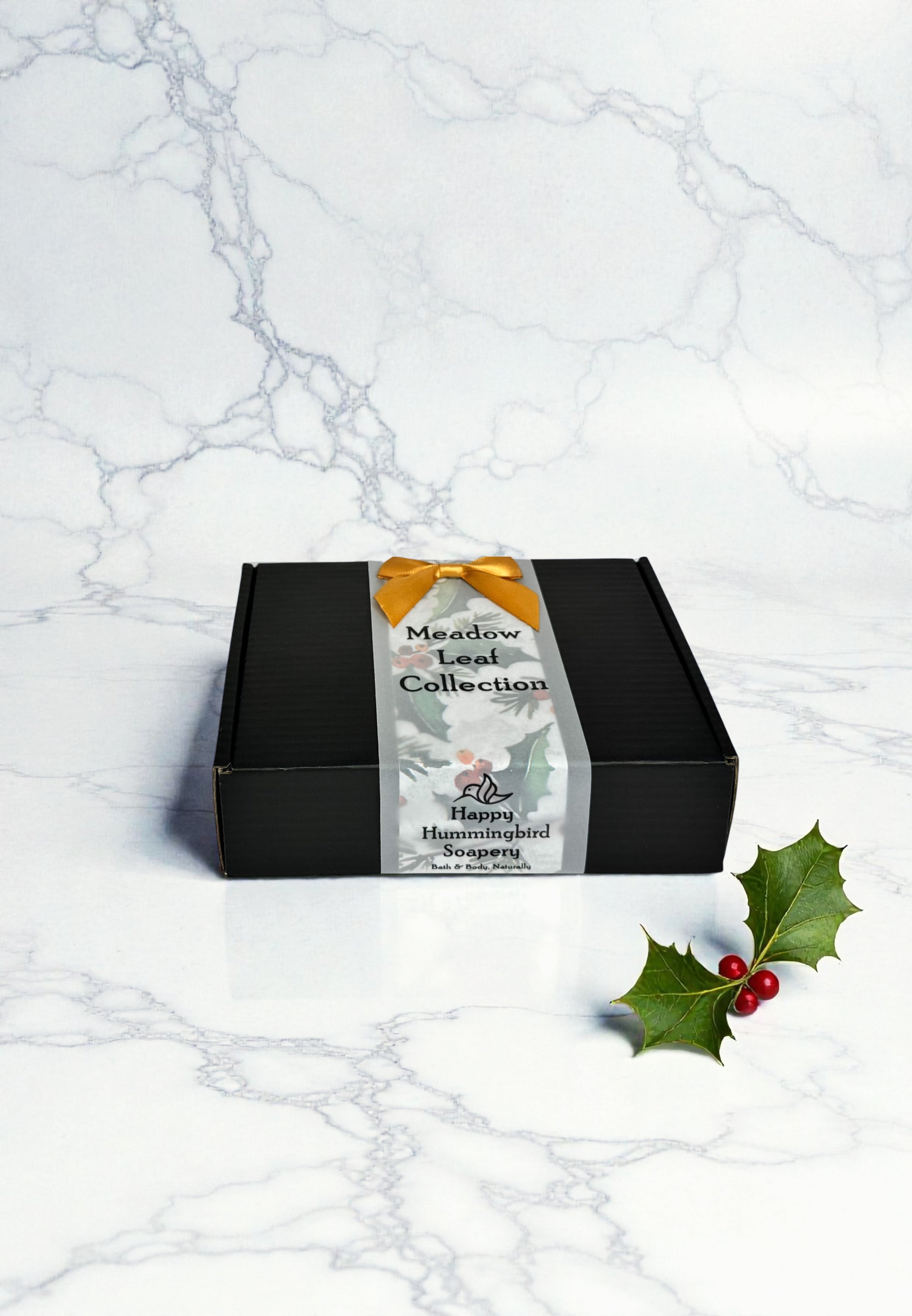 Meadow Leaf Collection closed black gift box with vellum belly band and gold satin bow — Happy Hummingbird Soapery.