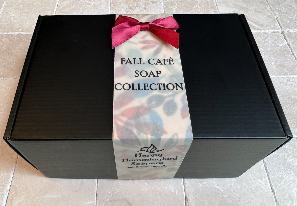 Closed matte black gift box for the Fall Café Collection, wrapped with an autumnal leaf patterned belly band and a deep red satin ribbon.