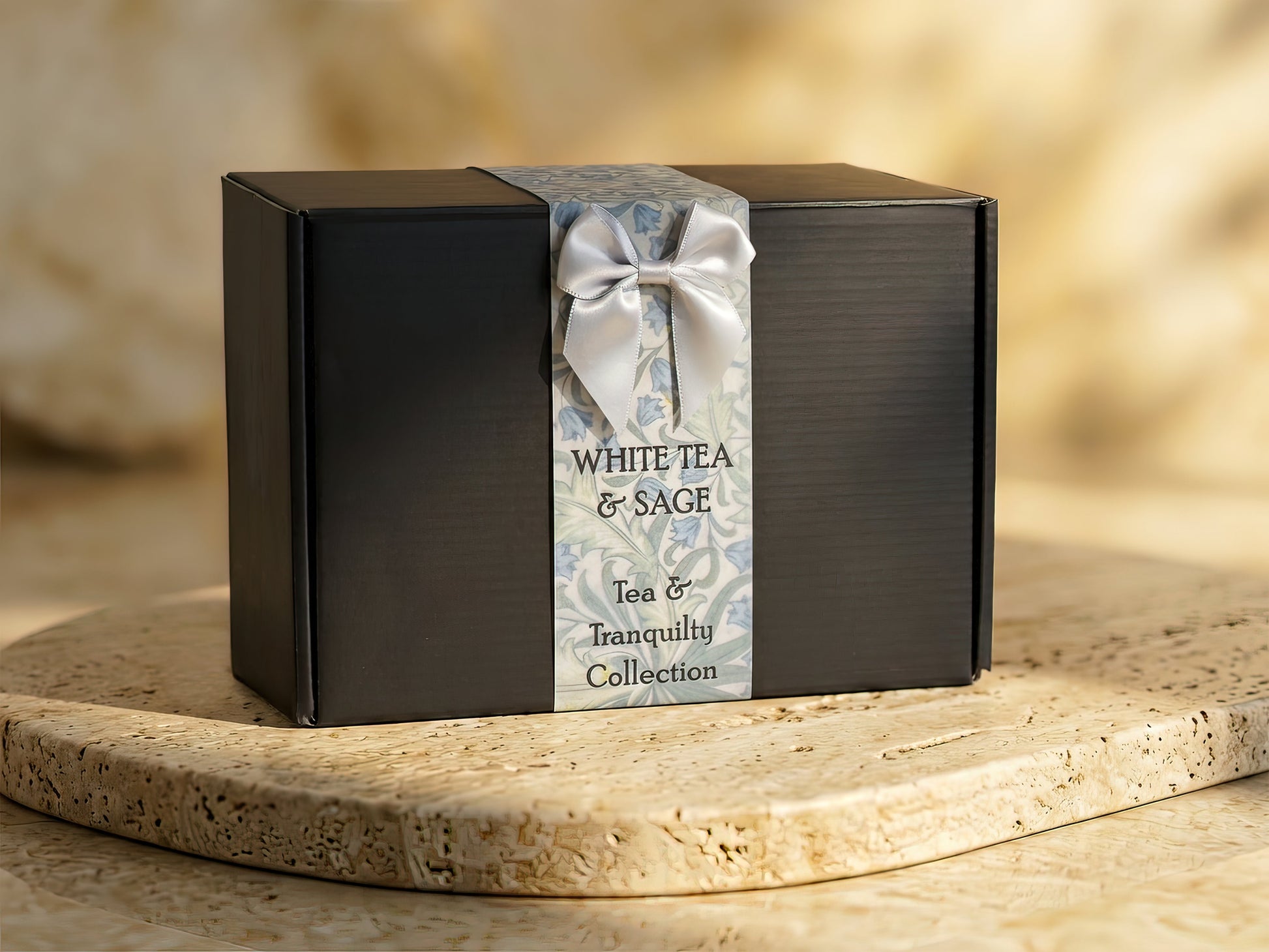 Premium black gift box from the White Tea & Sage Tea & Tranquility Collection, sitting on a natural travertine stone surface.
