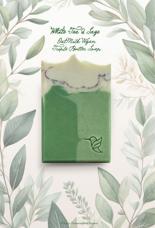 White Tea & Sage Soap by Happy Hummingbird Soapery. A cream-to-green rectangular bar with an embossed hummingbird logo, set against a botanical background.